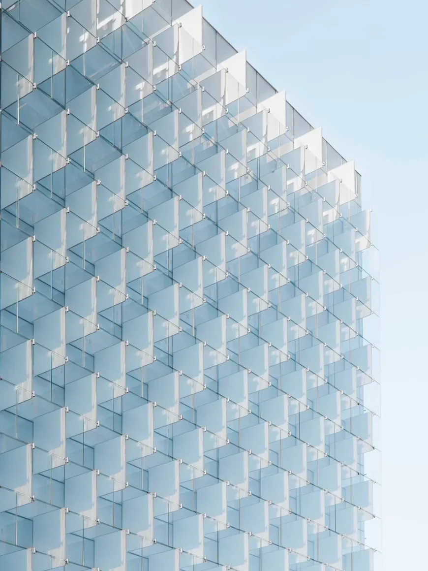 Faceted glass facade against a pale sky